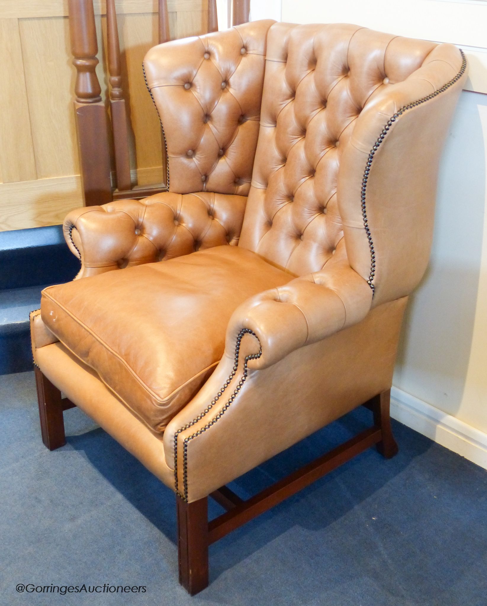 A George III style buttoned tan leather wingback armchair